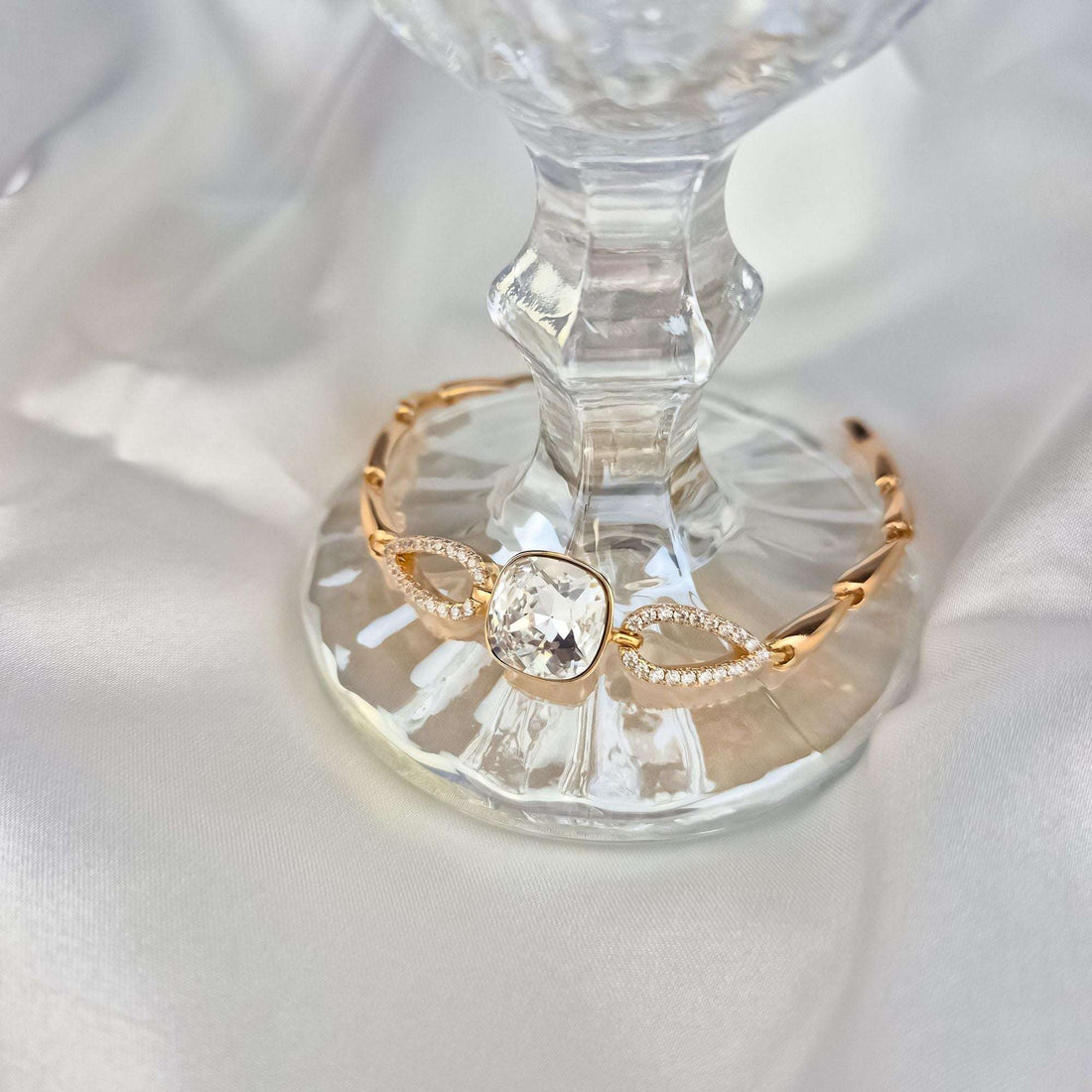 Aproce ar mirdzošu Swarovski kristālu uz stikla paliktņa, redzami cirkoniem rotātie posmi