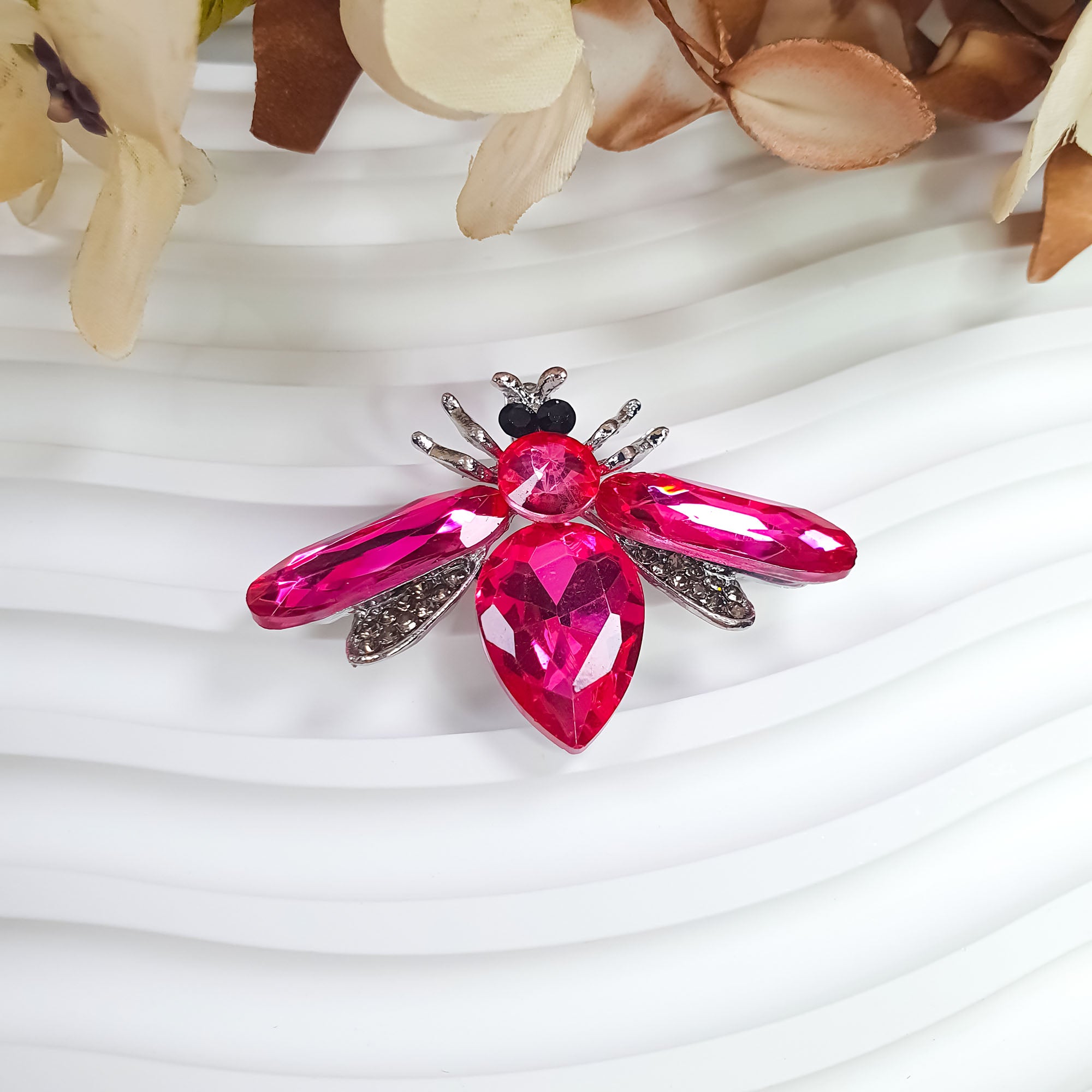 Taureņa piespraude ar šķautņotiem rozā spārniem