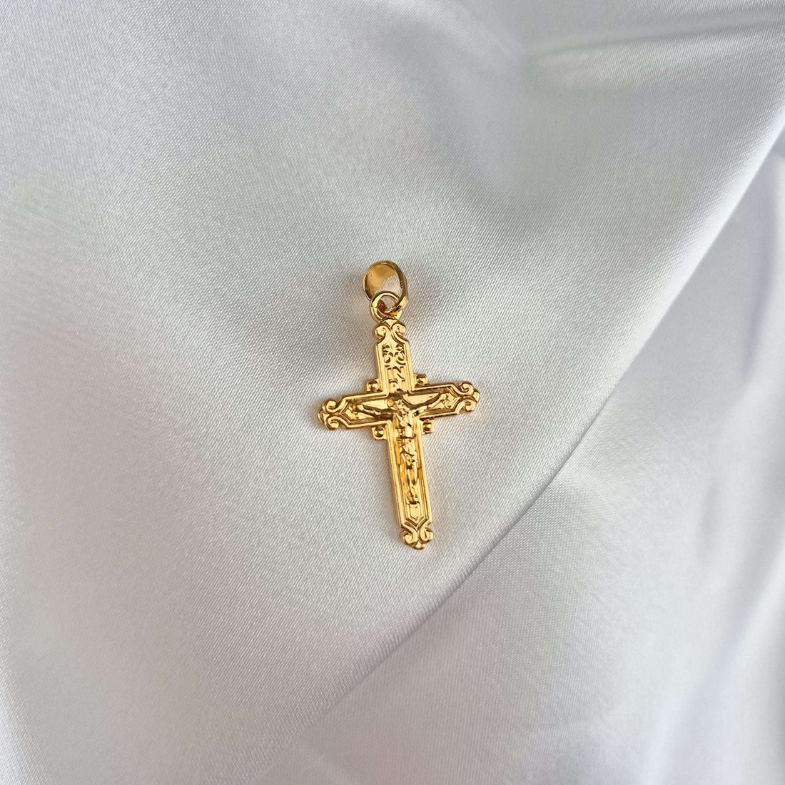 Apzeltīts katoļu krusta kulons ar Kristus figūru un INRI uzrakstu uz balta atlasa