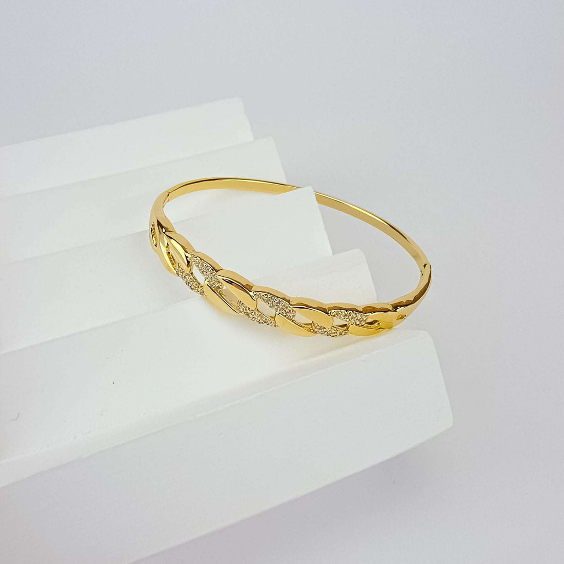 Apzeltīta cietā bangle rokassprādze ar ķēdes posmu rakstu un dzirkstošiem cirkoniem uz balta paaugstinājuma